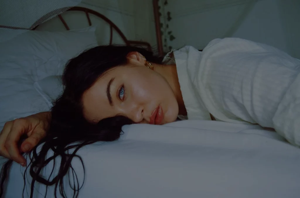 dark and dull image of a woman with blue eyes laying on the bed