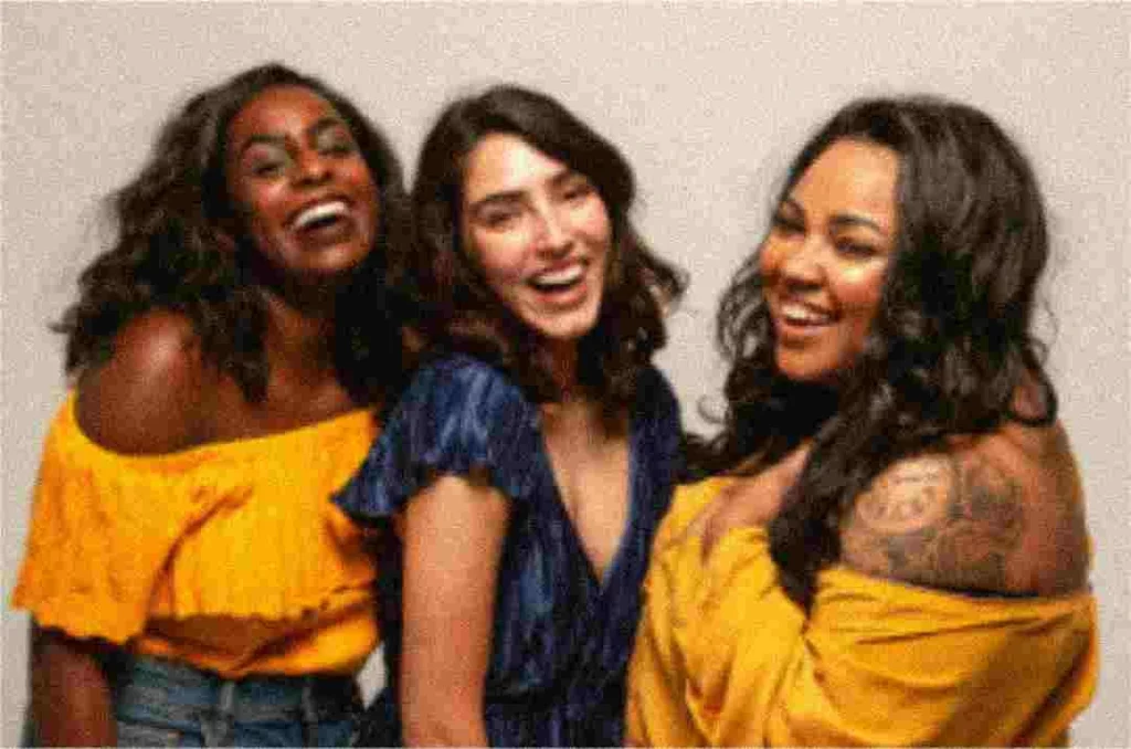 raw and blurry image of three woman laughing and smiling at the camera